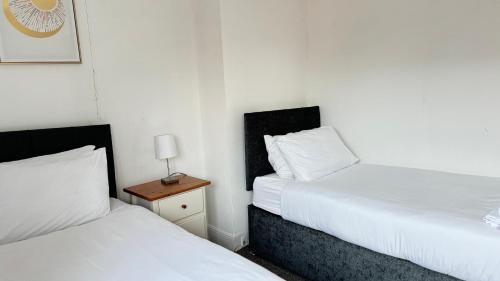 a bedroom with two beds and a night stand with a lamp at 4Bedroom house at Town Centre with Free Driveway Parking in Buckinghamshire