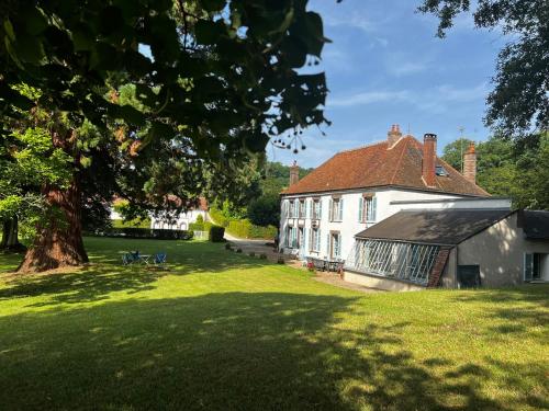a large white house with a tree in the yard at Le Chesnoy 17 pers piscine tennis in Parly