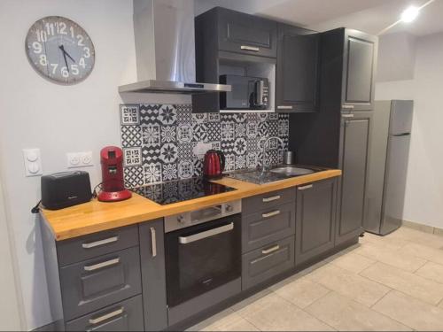 une cuisine avec des placards gris et une horloge murale dans l'établissement Maison de bourg vigneronne avec 3 chambres et tout confort, idéale pour la campagne ! - FR-1-586-44, à Menetou-Râtel