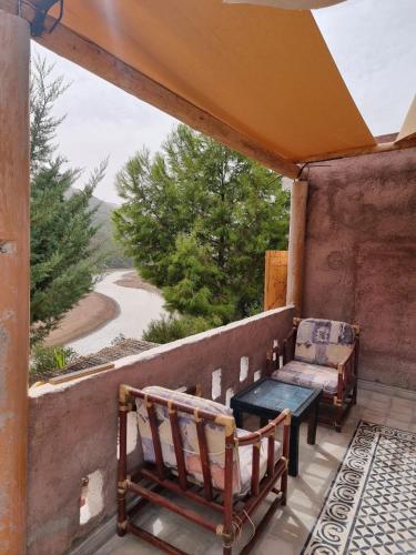 a porch with two chairs and a bench and a table at Dar l'eau Vive in Bine el Ouidane