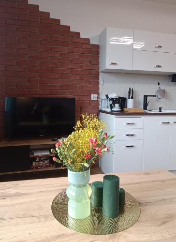 a vase with flowers on a table in a kitchen at Apartament Joanna in Reda
