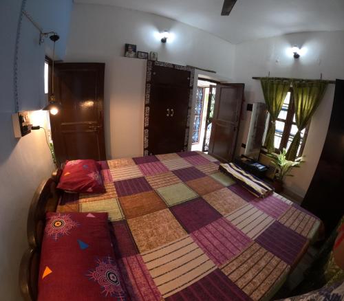 a bedroom with a bed with a quilt on it at Bagicha farmstay - Near Jolly Grant Airport in Doiwāla