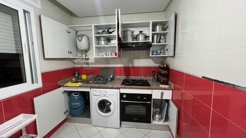 a red and white kitchen with a washing machine at Belle Appartement & Résidence Avec Piscine& A 10min de la plage- Martil-Tétouan in Martil