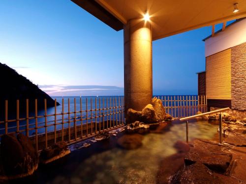 a hot tub with the ocean in the background at Hotel Kinparo in Toyooka