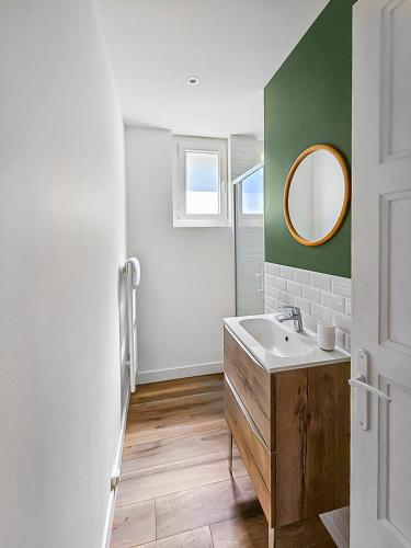 une salle de bain avec un lavabo et un miroir dans l'établissement Évasion Paisible au Creusot - T3 rénové et coloré, au Creusot