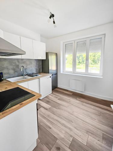 une cuisine avec des armoires blanches et un plancher en bois dans l'établissement Évasion Paisible au Creusot - T3 rénové et coloré, au Creusot