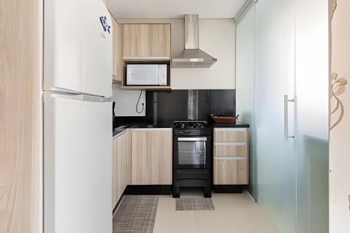 a small kitchen with a stove and a refrigerator at Summer Residence Vista Mar - Gov Celso Ramos/SC in Governador Celso Ramos