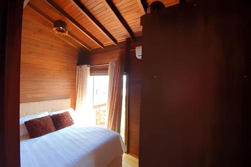 a bedroom with a white bed and a window at Chalé da Montanha com Ofurô in Santo Amaro da Imperatriz