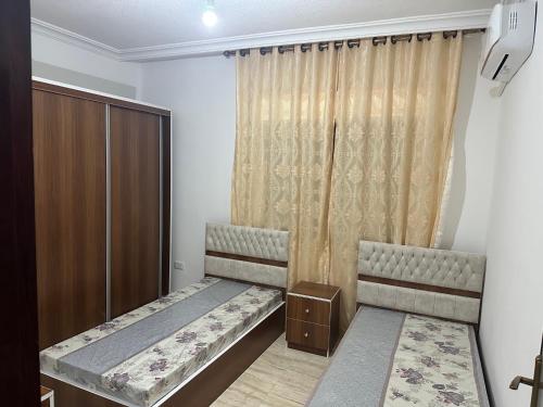 a bedroom with two beds and a curtain at Airport Road شارع المطار in Al Yādūdah