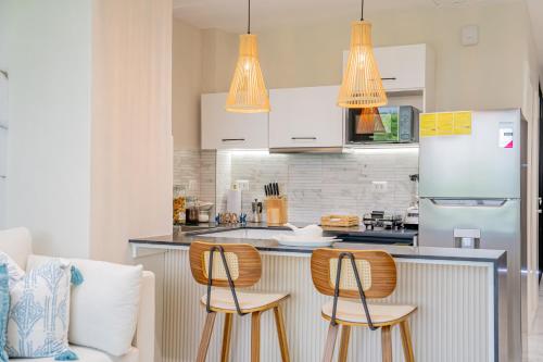 a kitchen with two chairs and a counter with a refrigerator at Xeliter Cana Rock Punta Cana in Punta Cana