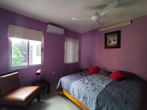 a bedroom with purple walls and a bed with red pillows at Casa La Güerita in Progreso