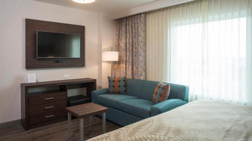 a hotel room with a bed and a couch and a television at Staybridge Suites Puebla by IHG in Puebla