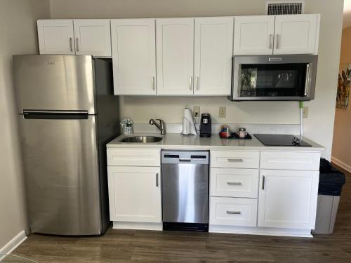 a kitchen with white cabinets and a stainless steel refrigerator at Summer Sands - 106 by Sea Scape Properties in Wrightsville Beach