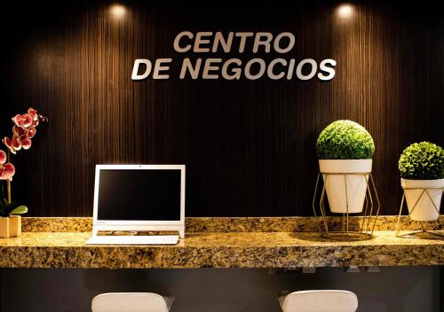 a desk with a laptop on a counter with plants at Hotel Diana del Bosque by DOT Urban in Morelia