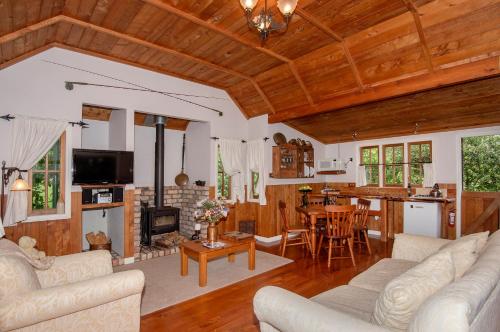 a living room with couches and a kitchen with a fireplace at Vineyard Cottages - Kumeu in Waimauku