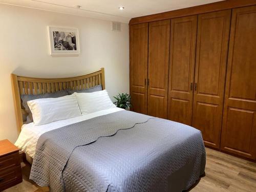 a bedroom with a bed and wooden cabinets at Garden flat in London in London
