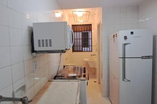 una cucina con forno a microonde e frigorifero di Ap Alecrim Praia do Forte Cabo Frio Pé na Areia3qt a Cabo Frio