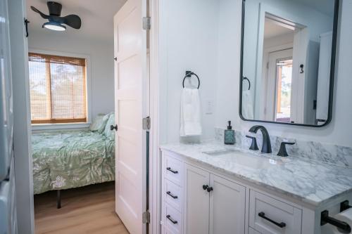 Un baño con lavabo, espejo y cama. en Contained in Gruene! Hot Tub!, en New Braunfels