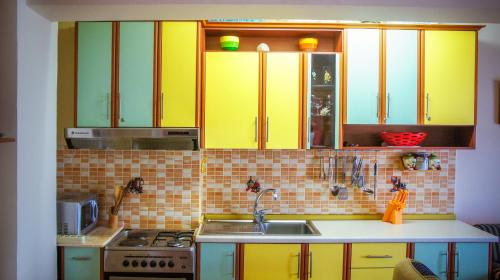 a kitchen with yellow cabinets and a sink at BELVEDERE Shengjin in Lezhë