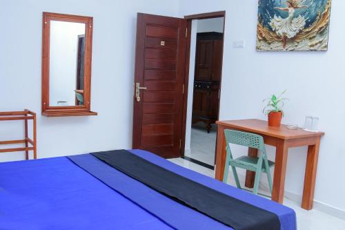 a bedroom with a bed and a desk and a table at Villa 34 in Ambalangoda