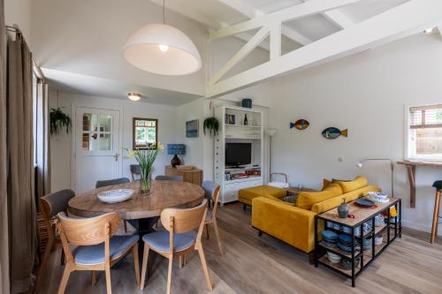 a living room with a table and a yellow couch at Beautifully located dune villa near Noordwijk beach in Noordwijk