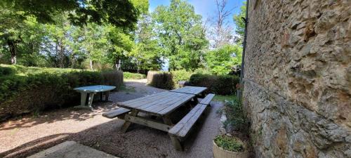 - une table de pique-nique en bois à côté d'un mur en pierre dans l'établissement Le Manoir de Sonnac, à La Cresse
