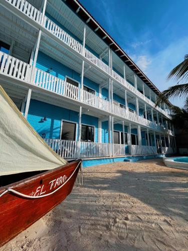 a boat on the beach in front of a building at El Faro Beach Front by ÓOL Hotels in Holbox Island