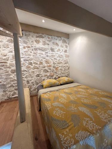 une chambre avec un lit et un mur en pierre dans l'établissement Le ruisseau, à Nice