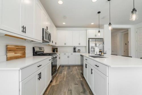 a white kitchen with white cabinets and wooden floors at Private Pool! Avondale - Modern Mtn View Oasis in Cashion