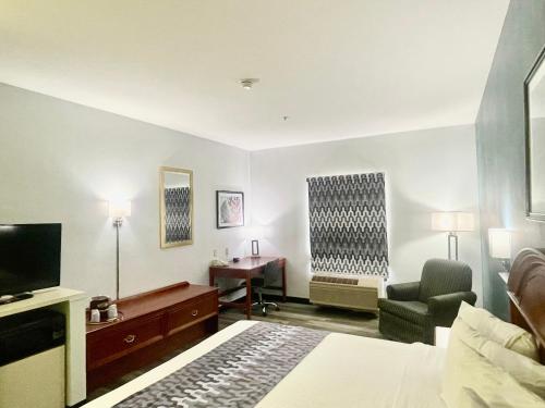 a hotel room with a bed and a chair and a desk at Grand Vista Hotel & Suites in Vonore