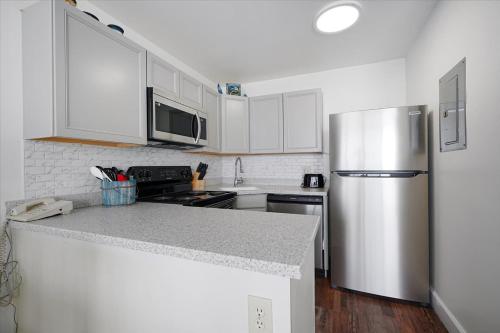 a kitchen with white cabinets and a stainless steel refrigerator at Atlantic Towers 1007 by Sea Scape Properties in Carolina Beach