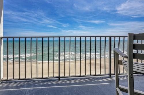 a bench sitting on a balcony looking at the beach at Atlantic Towers 1007 by Sea Scape Properties in Carolina Beach