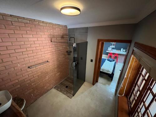 a bathroom with a walk in shower next to a brick wall at Nectar Game Lodge in Buffelspoort