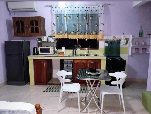 a small kitchen with a table and white chairs at Anne Hillside Apartment in Victoria