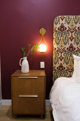 a nightstand with a vase on it next to a bed at Adobe Inn in Monterey Park