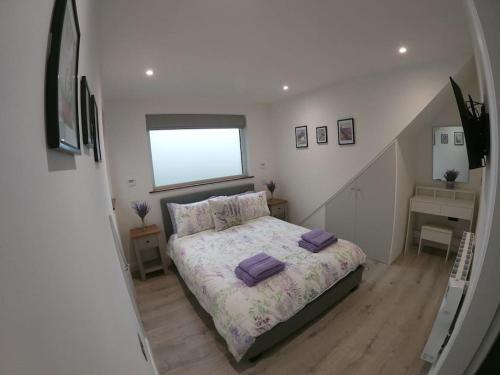 a bedroom with a bed with purple pillows on it at Lavender Lodge - Modern apartment in York in Copmanthorpe