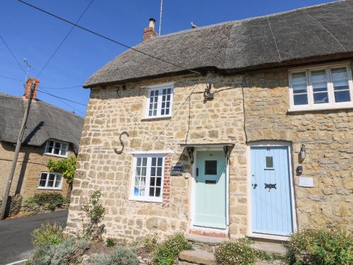 an old stone house with a thatched roof at Dormouse Cottage in Bridport