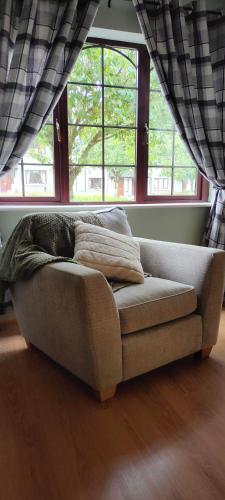 a couch sitting in a living room with windows at Rynn Haven - Enchanting Townhouse Lough Rynn in Mohill