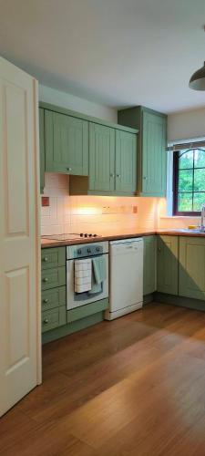 a kitchen with green cabinets and white appliances at Rynn Haven - Enchanting Townhouse Lough Rynn in Mohill