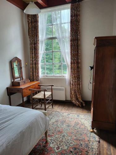 a bedroom with a bed and a desk and a window at Zuidewijn in Sprang-Capelle