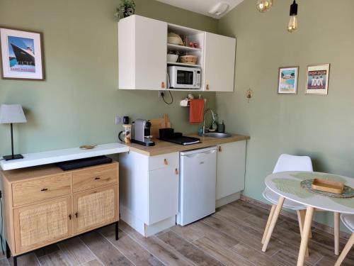 a kitchen with white cabinets and a table at Air marin in La Bernerie-en-Retz