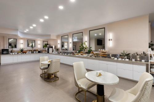 a kitchen with white chairs and tables and a counter at Ramada by Wyndham DFW Airport in Irving