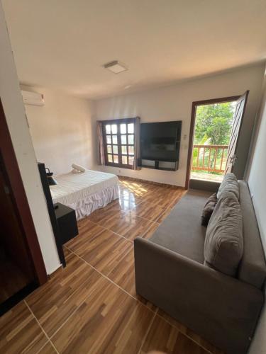 a living room with a couch and a flat screen tv at Pipa Golfinhos Pousada in Pipa