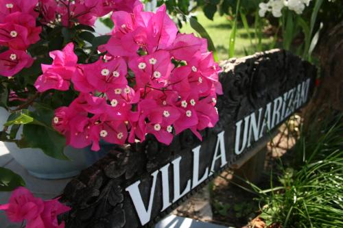 a sign with pink flowers in a garden at Villa Unarizaki in Iriomote