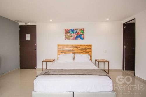 una camera da letto con un grande letto bianco con due tavoli di Mountain and City Views Loft Ultra-Fast Internet a Medellín
