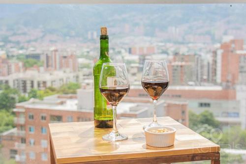 una bottiglia di vino e due bicchieri su un tavolo di Mountain and City Views Loft Ultra-Fast Internet a Medellín