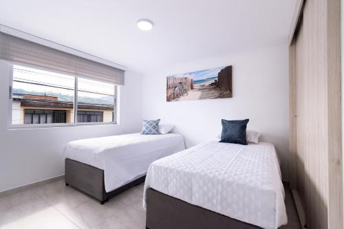 two beds in a room with a window at Refugio Moderno para descansar en Santa Rosa in Santa Rosa de Cabal