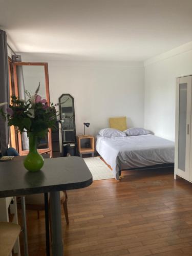 a bedroom with a bed and a table with a vase of flowers at Studio avec terrasse sur jardin in Fontenay-sous-Bois