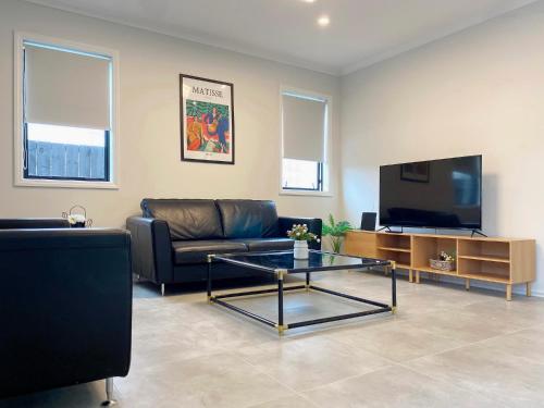 a living room with a couch and a tv at Extra-Large Brand-New House, Over 400sqm in Auckland