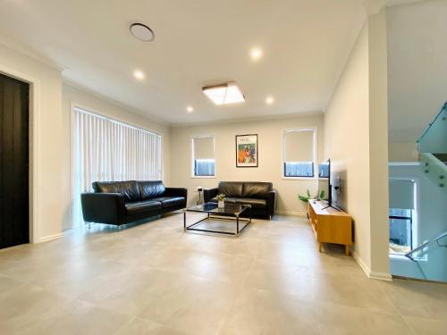 a living room with a couch and a table at Extra-Large Brand-New House, Over 400sqm in Auckland